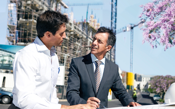 Zwei Männer im Gespräch vor einer Baustelle