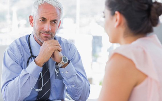 Serious doctor listening to patient explaining her painful in his office